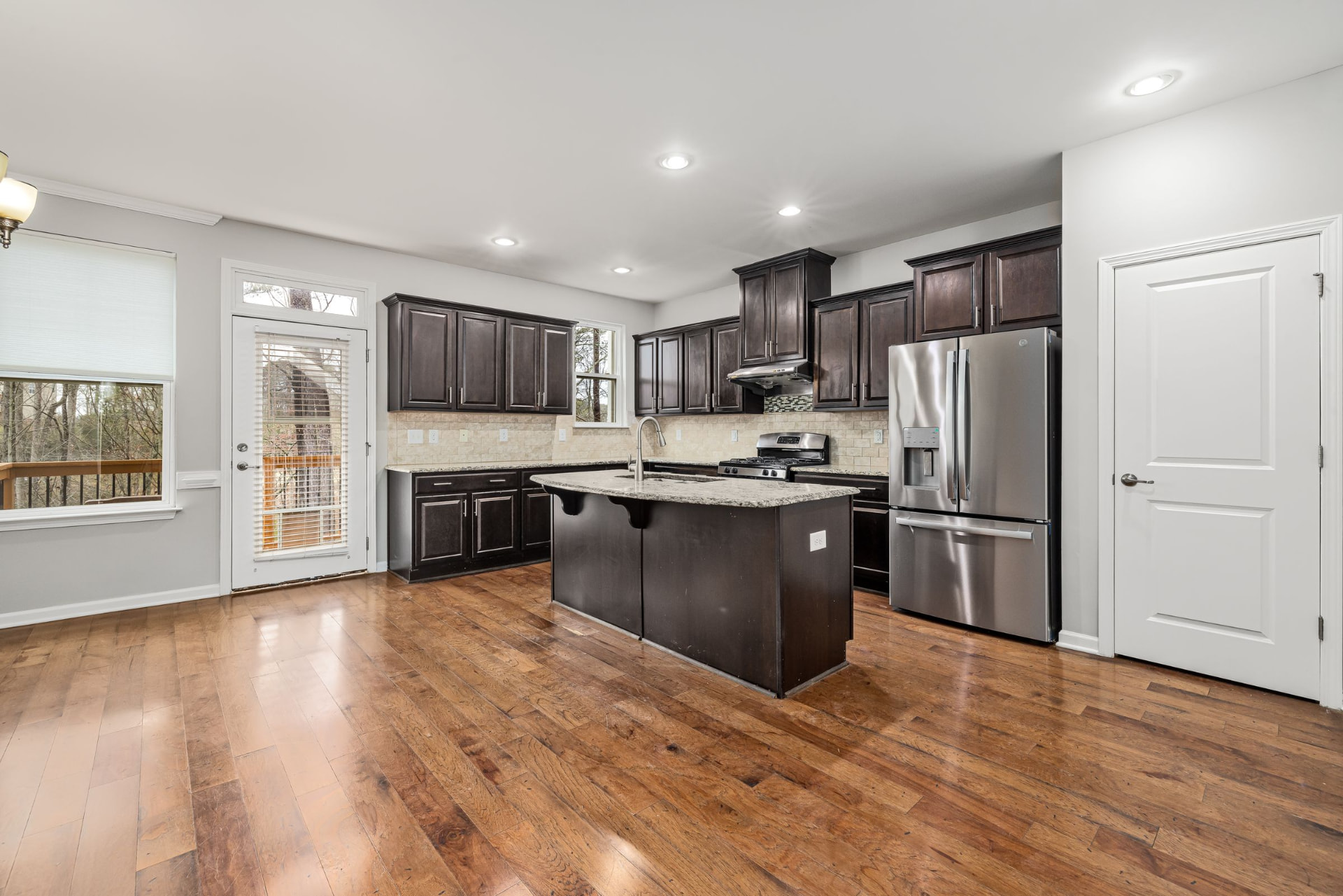 Espresso kitchen cabinets with a granite island in an empty new-build home
